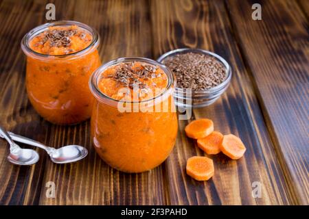 Karotten-Smoothies oder pürieren Sie mit Leinsamen im Glas Gläser auf der Holzoberfläche Stockfoto