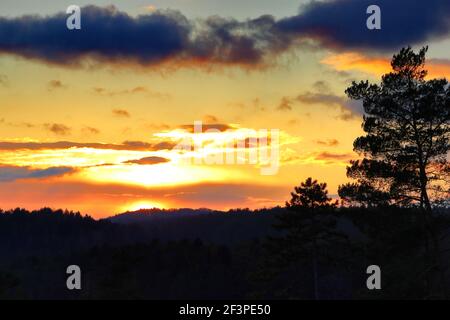 Landschaftlich schöner Sonnenuntergang mit einem bunten Himmel über den Wäldern Stockfoto