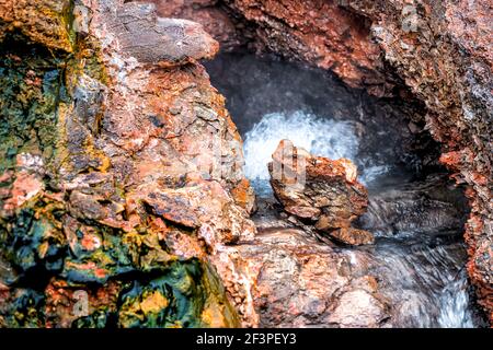 Nahaufnahme von Dampfgeysir in Deildartunguhver heißen Quellen in Island Mit rotem Felsen bunte Höhle Öffnung Loch und Wasser kochend Stockfoto