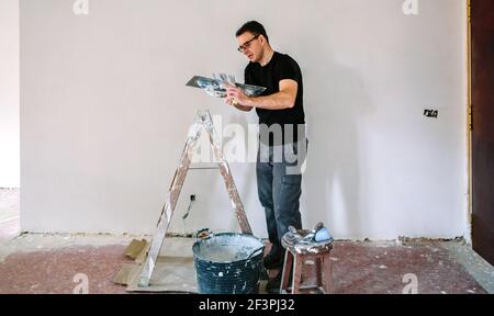 Baumeister arbeiten Pflücken Gips mit Spachtel Stockfoto