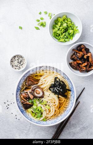 Vegane Shiitake Pilz Ramen Nudeln Schüssel auf einem grauen Beton Hintergrund, Tischansicht von asiatischer Küche Stockfoto