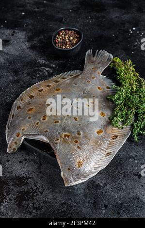 Roher Flunder Plattfisch auf Marmorplatte mit Thymian. Schwarzer Hintergrund. Draufsicht Stockfoto