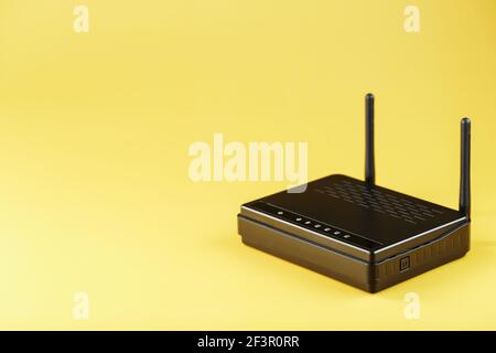 Wi-Fi-Router in schwarz auf gelbem Hintergrund mit freiem Speicherplatz. Internetanschlusskonzept Stockfoto