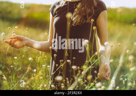 Mittelteil Porträt boho Stil Kleid junge Frau zu Fuß im Gras und Wildblumen mit der Natur verbinden. Konzept: Spiritualität, Zen, Balance Stockfoto