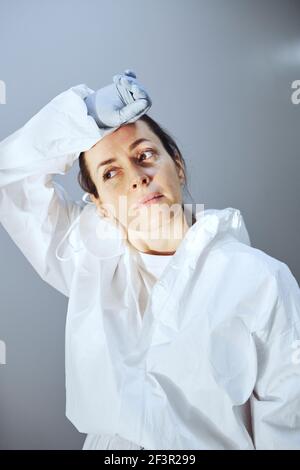 Müde Ärztin in Schutzuniform, die am Krankenhausflur steht Stockfoto