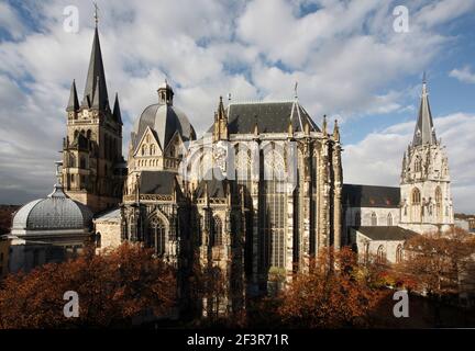 Außenansicht der Pfalzkapelle und der Kirche St. Follian mit roten Blattbäumen im Vordergrund in Aachen, Deutschland Stockfoto