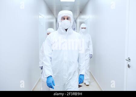 Gruppe von Ärzten in Schutzuniformen, die den Korridor entlang gehen Im Krankenhaus während einer Pandemie Stockfoto