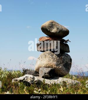 Ein Stapel Steine im Gleichgewicht. Die Steine sind rau und der Stapel steht auf einem Grasfeld Stockfoto