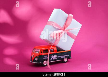 Kiew Ukraine - 11. März 2021. Spielzeugmodell des Volkswagen Typ 2, T1, Pickup 2 mit Geschenkkarton auf dem Brett auf kräftigem rosafarbenem Hintergrund mit Schatten. Stockfoto