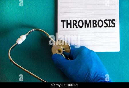 Symbol für Medizin und Thrombose. Arzthand, Stethoskop. Weiße Note mit dem Wort 'Thrombose'. Schöner blauer Hintergrund. Arzt Hand in blauen Handschuh. Stockfoto