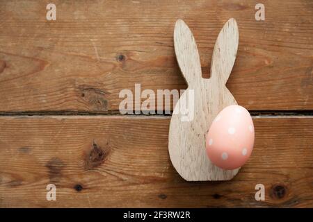 Minimale osterferien Hintergrund. Osterhase und Ei aus Holz auf Holzbrett Stockfoto