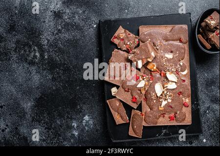 Handwerk hausgemachte Schokoladen-Bars auf Marmorplatte gehackt. Schwarzer Hintergrund. Draufsicht. Speicherplatz kopieren Stockfoto