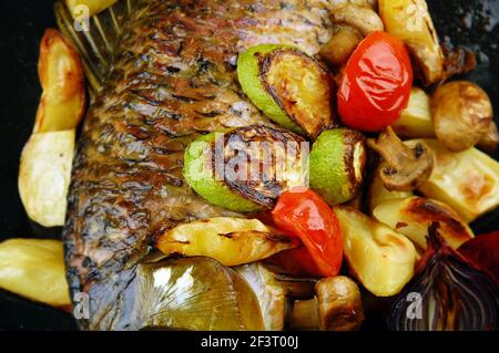 Gebackener Fisch mit Gemüse, Pilzen und Zitrone. Fokus auf einem mittleren Bild. Stockfoto