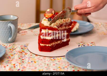 Von Hand ein Stück Red Samt Schicht Kuchen schneiden Stockfoto