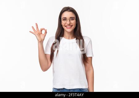 Taille-up-Porträt von optimistischen, lächelnd glücklich junge hübsche Frau in einer Brille, zeigt okay Zeichen, zustimmen oder empfehlen etwas, geben positive Bewertung Stockfoto