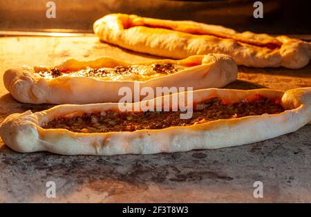 Traditionelle türkische Fladenbrote, bekannt als Kasarli suculu Pide und Kiymali Pide, werden auf heißem Stein in einem Vintage-Ofen gebacken. Dieses Boot geformt Pas Stockfoto