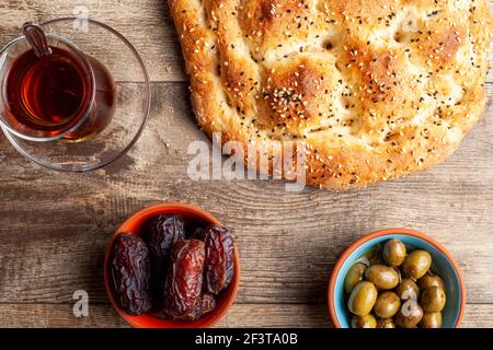 Flaches Lay-Bild einer traditionellen Mahlzeit für Iftar und Sahur im heiligen Fastenmonat Ramadan. Türkischer Tee in speziellen Gläsern, ramazan Pidesi, ein Typ Stockfoto