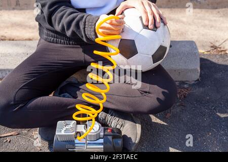 Nahaufnahme einer kaukasischen Frau mit Fußball Kugel- und Einstecknadel-Bit am Ende des Gelber Spiralschlauch, der an 12V Car tir befestigt ist Stockfoto