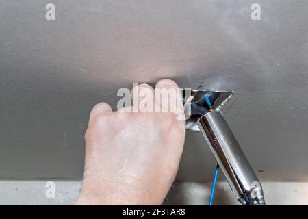 Der Elektriker löt die verdrillten elektrischen Drähte mit einem Gurt in die Steckdose. Installation von Kommunikation und Isolierung von Drähten. Stockfoto