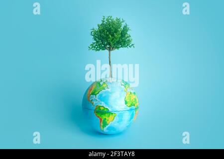 Ökologie und Umweltschutz Konzept. Lebender Baum wächst vom Planeten Erde auf einem reinen farbigen Hintergrund. Erhaltung der Natur. Stockfoto