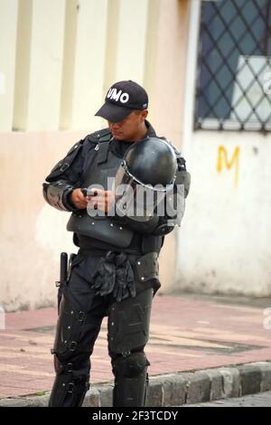 Polizeibeamter im Aufstandsgewerk mit einem Handy bei Inti Raymi, dem indigenen Sonnenwende-Festival in Cotacachi, Ecuador Stockfoto