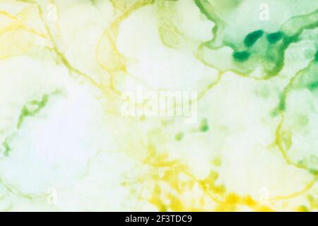 Makro-Nahaufnahme von verschwommenen gelben und grünen Farbschichten und Spritzern, abstrakter Hintergrund. Flüssige Tinte, farbenfroher, strukturierter Hintergrund im Vollformat. Stockfoto