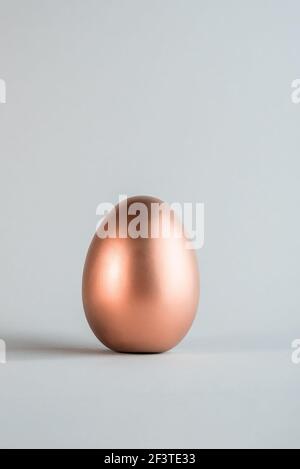 Große Rose Gold Farbe Osterei auf einem einfachen grauen Hintergrund. Main christian Urlaub minimalistischen Hintergrund. Stockfoto