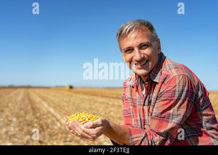 Farmer's Hands Holding Erntekorn. Happy Farmer mit Maiskörnern in den Händen Blick auf Kamera. Stockfoto