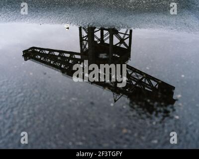 Alternative Ansicht des ehemaligen Clydeside Schiffbaus Finnieston Crane, bekannt als Titan, reflektiert in Pfützen in der Dämmerung, Glasgow, Schottland. Stockfoto