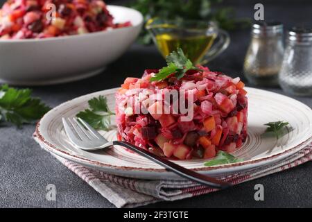 Traditionelle Salat Vinaigrette von Rüben, Kartoffeln, Karotten, Bohnen, Gurken, Zwiebeln und Pflanzenöl auf grauem Hintergrund. Vegetarisches Essen Stockfoto