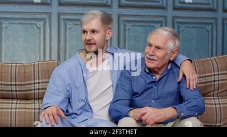 Familie von älteren Vater und erwachsenen Sohn oder Enkel mit Unterhaltung Chatten Entspannen auf der Couch Stockfoto
