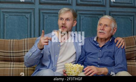 Familie älterer Mann Vater und erwachsenen Sohn sitzen auf dem Sofa Sportspiel im Fernsehen mit Popcorn essen Stockfoto
