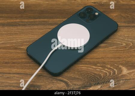 Czernivtsi, Ukraine - März, 2021: Laden mit dem neuen MagSafe Wireless-Ladegerät das neueste iPhone 12 Pro Max 5G Smartphone-Modell von Apple Computers Stockfoto