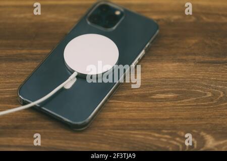 Czernivtsi, Ukraine - März, 2021: Laden mit dem neuen MagSafe Wireless-Ladegerät das neueste iPhone 12 Pro Max 5G Smartphone-Modell von Apple Computers Stockfoto