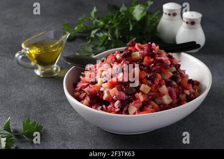 Traditionelle Salat Vinaigrette von Rüben, Kartoffeln, Karotten, Bohnen, Gurken, Zwiebeln und Pflanzenöl auf grauem Hintergrund. Vegetarisches Essen Stockfoto