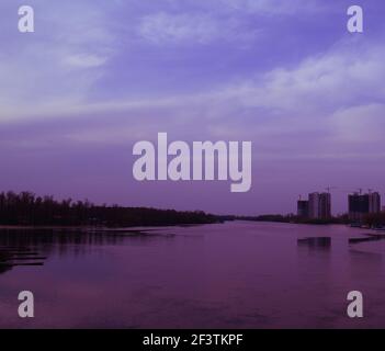 Der Blick über den Fluss ist breit für zwei Häuser in der Ferne. Abends Stadtlandschaft Stockfoto