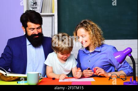 Zurück zur Schule. Schüler lernen Buchstaben und Zahlen. Bildungsprozess. Schulfamilie. Kleines Kind bereit zu studieren. Fröhliche Familie spielt mit Sohn. Stockfoto