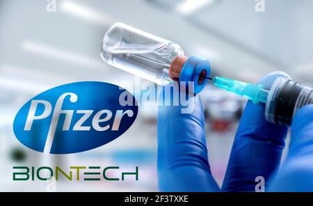 CLUJ-NAPOCA -RUMÄNIEN - MÄRZ 9 2021: Pfizer-Impfstoff Covid-19 Konzept. Spritzennadel und Impfstoff, verschwommenes Firmenlogo von Pfizer auf dem Hintergrund. Stockfoto