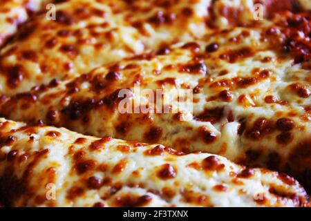 Nahaufnahme einer Pizza mit geschmolzenem Käse bedeckt und in Scheiben geschnitten. Stockfoto