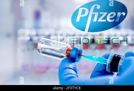 CLUJ-NAPOCA -RUMÄNIEN - MÄRZ 9 2021: Pfizer-Impfstoff Covid-19 Konzept. Spritzennadel und Impfstoff, verschwommenes Firmenlogo von Pfizer auf dem Hintergrund. Stockfoto