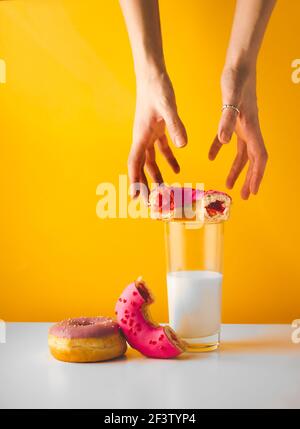 Hände, die nach gesunden Donuts auf gelb greifen Stockfoto