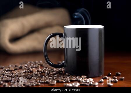 A studio photo of steaming coffee in a cup and coffee beans. Stock Photo