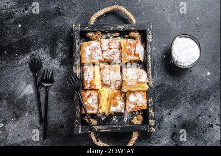 Geschnittenes Bougatsa-Pie-Gebäck mit Grießpudding-Creme. Schwarzer Hintergrund. Draufsicht Stockfoto