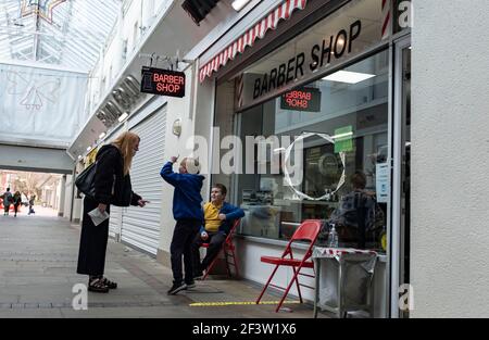 Carmarthenshire, Großbritannien. März 2021, 17th. Eine Frau mit Kindern wartet vor einem Friseursalon in Wales, Großbritannien.Acht weitere Menschen sind in Wales an Coronaviren gestorben und die Infektionsrate ist insgesamt leicht angestiegen. Kredit: SOPA Images Limited/Alamy Live Nachrichten Stockfoto