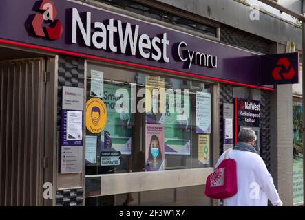 Carmarthenshire, Großbritannien. März 2021, 17th. Eine Frau geht an einer NatWest-Bank in Wales vorbei.Acht weitere Menschen sind in Wales an einem Coronavirus gestorben und die Infektionsrate ist insgesamt leicht angestiegen. Kredit: SOPA Images Limited/Alamy Live Nachrichten Stockfoto