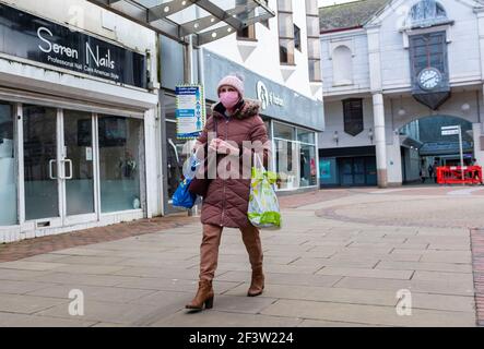 Carmarthenshire, Großbritannien. März 2021, 17th. Eine Frau, die eine Maske als vorbeugende Maßnahme gegen die Ausbreitung von covid-19 trägt, trägt Einkaufstaschen beim Spaziergang entlang einer Straße in Südwales, Großbritannien.Acht weitere Menschen sind in Wales an Coronavirus gestorben und die Gesamtinfektionsrate ist leicht gestiegen. (Foto von May James/SOPA Images/Sipa USA) Quelle: SIPA USA/Alamy Live News Stockfoto