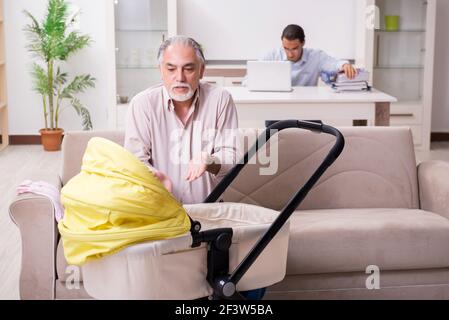 Alter Großvater, der sich zu Hause um das Neugeborene gefreut hat Stockfoto