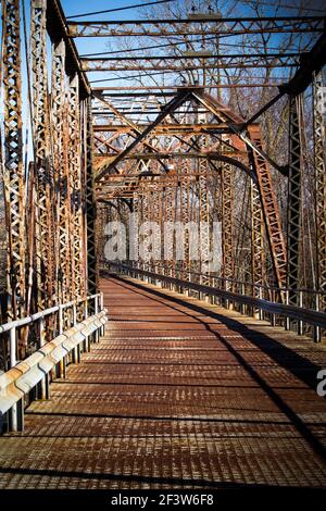 Old rusty single lane curved  bridge over the river. Stockfoto