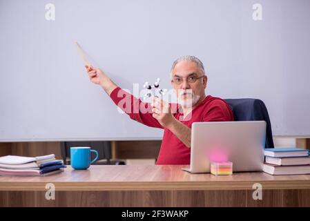 Erfahrener Lehrer Physiker sitzt im Klassenzimmer Stockfoto