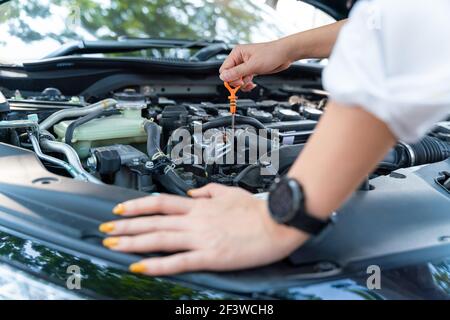 Nahaufnahme Hand der Frau überprüfen Sie den Ölstand im Motor Auto. Stockfoto